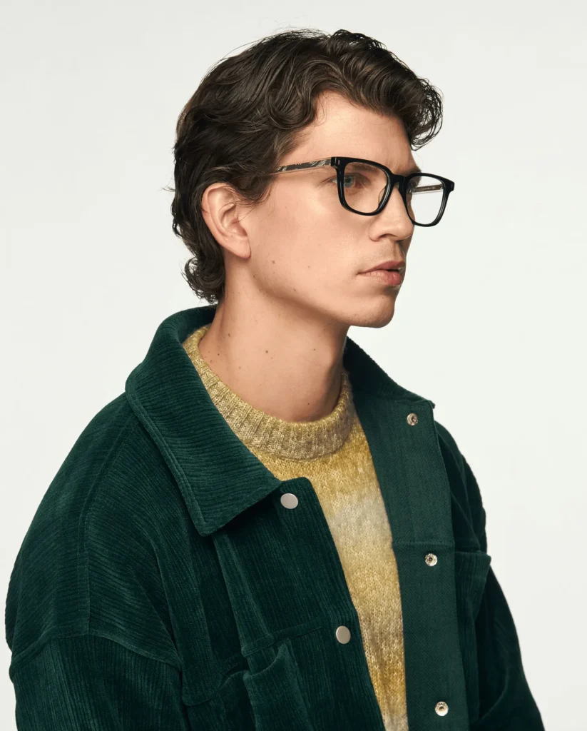 グリーンのジャケットを着たモデルが着用するスクエア型アイウェア